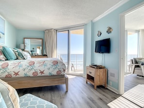 Cozy bedroom with sea-themed decor, offering direct access to a private balcony and breathtaking ocean views.