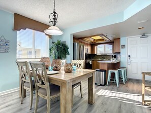 Spacious dining area leading to a fully-equipped kitchen, perfect for family meals and gatherings with an ocean ambiance.