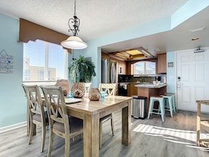 Spacious dining area leading to a fully-equipped kitchen, perfect for family meals and gatherings with an ocean ambiance.