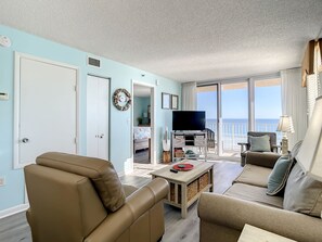 Bright and comfortable living room with direct ocean views, cozy seating, and coastal decor, perfect for relaxation and entertainment.
