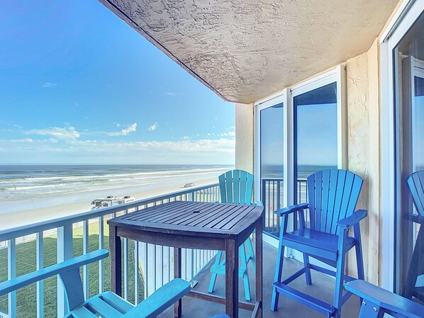 Relax on the balcony with comfortable seating and stunning ocean views for a perfect beach retreat.