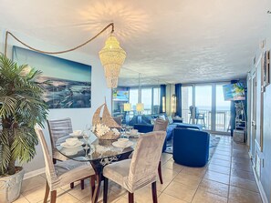 Coastal-themed dining area leading to a spacious living room with large windows and ocean views.