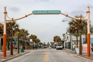 The welcoming arch of Flagler Avenue invites visitors to explore its lively beachside street, lined with palm trees, shops, and dining spots in this scenic coastal town.