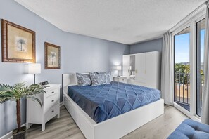This spacious bedroom offers a comfortable king-sized bed, modern furnishings, and direct access to a private balcony. The serene decor and natural light create a perfect retreat for relaxation and enjoying the coastal views.