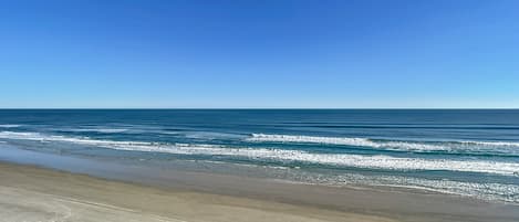 Enjoy the calming views of the expansive blue ocean meeting the horizon under clear skies.