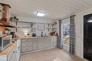 The quaint kitchen has original shiplap walls & ceiling.