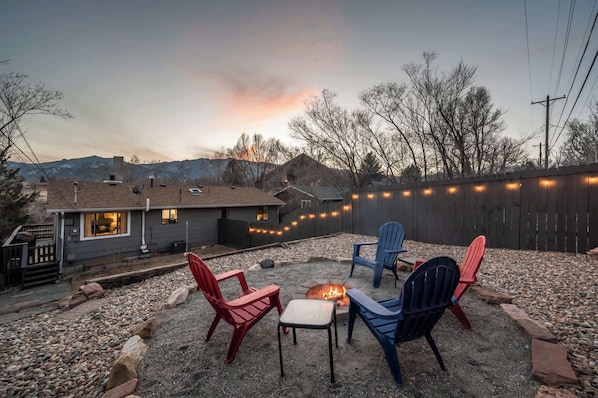 Cozy fire pit area with Adirondack seating and mountain views—perfect for evening relaxation under the string lights.

