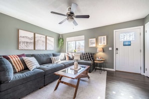 Bright and inviting living room with a spacious sectional, cozy textures, and natural light—perfect for relaxing or gathering.

