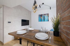 A chic dining area with a rustic wooden table, elegant tableware, and an industrial-style pendant light, blending modern and vintage aesthetics.

