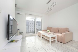 Another view of the living room, showcasing the pink sofa and a mounted flat-screen TV.
