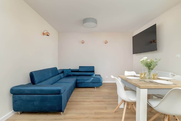 A wider look at the navy-blue corner sofa and round dining table, emphasizing the functional layout.