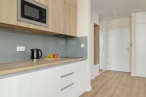 A closer look at the kitchen with built-in wooden cabinets and a sleek, handle-free design, plus a microwave set at a convenient height.