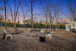Relax in the back yard with a large firepit area, string lights, and a separate outdoor patio and dining area.