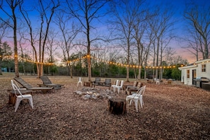 Relax in the back yard with a large firepit area, string lights, and a separate outdoor patio and dining area.