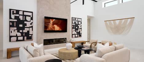 Grand open-concept living space with designer decor, featuring a fireplace and Smart TV.