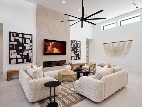 Grand open-concept living space with designer decor, featuring a fireplace and Smart TV.
