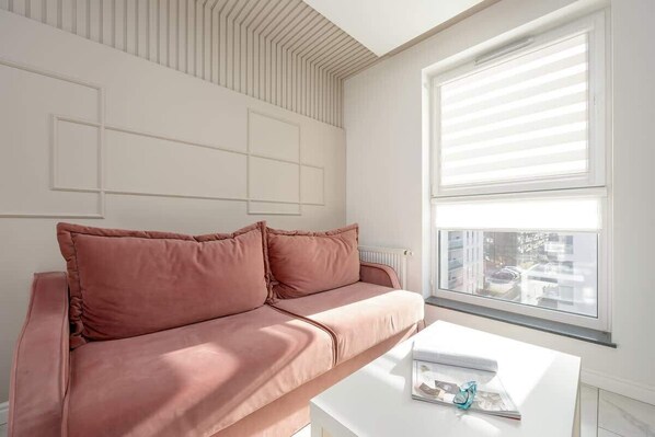 A cozy seating area with a pink cushioned bench by a large window, allowing in plenty of natural light.
