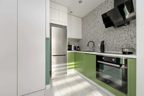 A stylish kitchen featuring green lower cabinets, white upper cabinets, and a mosaic-patterned backsplash.
