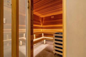 A luxurious wooden sauna with warm lighting and neatly arranged seating.
