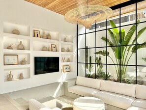 Sunken lounge with a Tv, niches, and a garden view