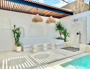 Outdoor area with a shaded white lounge, and a limestone shower