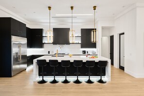 Fully equipped kitchen boasting high-end stainless-steel appliances, and a large island offering bar seating.