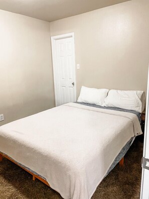Cozy queen bed with fresh linens and warm lighting.