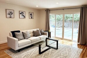 Living room with 65" HDTV, boardgames, a comfortable sofa, and floor cushions