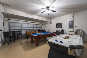 Garage has been converted to a games room and features high top table with chairs, foosball, pool table and air hockey.