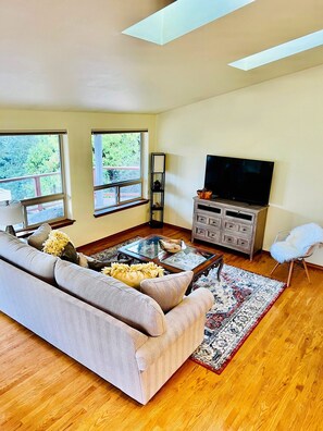 Second floor has spacious, living room area with many windows and skylights. 