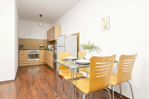A dining area with a wooden table and chairs, connected to an open kitchen, allowing for easy and stylish meal preparation.

