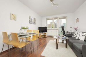 A spacious open-plan dining and living area with a wooden floor, warm lighting, and a contemporary decor scheme.

