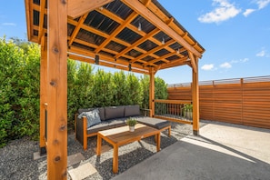 Wood pergola offers shade and a comfortable couch, with lush greenery