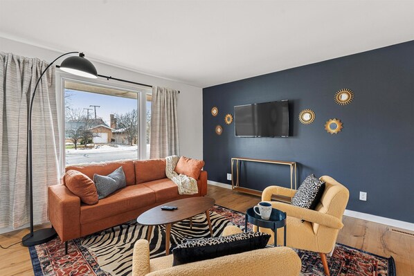 Living room with tv, floor lamps, and windows with curtains