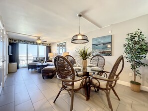 Dine and relax in this airy, ocean-view room featuring cozy wicker furnishings, stylish decor, and natural light flowing in through large sliding doors. Perfect for coastal comfort.