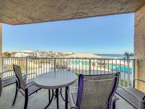 Enjoy serene moments on this private balcony, complete with seating and stunning views of the ocean and nearby pool area. Ideal for relaxation and fresh coastal breezes.
