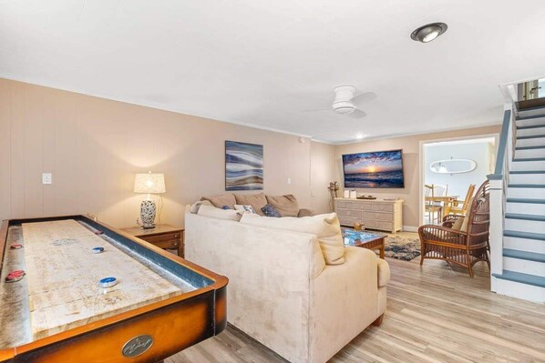 Living room featuring a large sectional couch and smart TV with the ability to log into personal streaming platforms and shuffle board