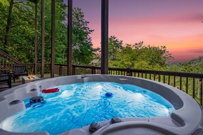 Hot tub relaxation with a stunning sunset and tree-lined horizon