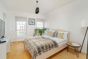 A cozy bedroom with a neatly made bed, a floor lamp, and soft textures, creating a warm and inviting atmosphere.

