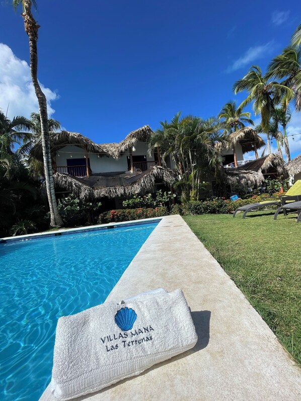 Piscina grande en el Jardin grande de un verdor y palmeras