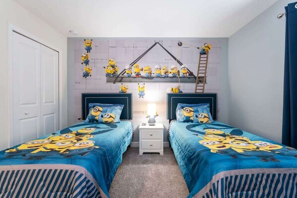 Delight your kids with this fun-themed bedroom, featuring cozy twin beds and a playful mural that sparks imagination.