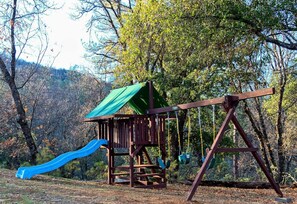 Children will love the wooden play set in the shade of the oak trees