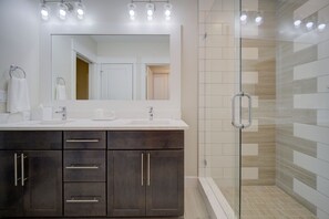 A well-appointed bathroom featuring dark cabinetry and a walk-in shower.