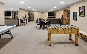Activity room with air hockey table, foosball table, PacMan arcade game, xbox, Smart TV, puzzles, coloring books, games, poker table, and books. 