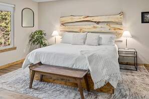 Bedroom with ensuite bathroom, king size bed, birch headboard, closet with luggage rack, and a Smart TV. The bed is on a wooden platform to give you a quiet sleeping experience.                       