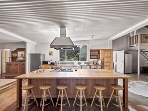 Cook with ease in a gourmet, rustic kitchen featuring a generous island bench, gas cooktop, oven, dishwasher, and everything needed for shared feasts or quick snacks.
