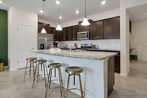 Craft your favorite dishes in a fully-equipped kitchen, featuring rich dark cabinetry and gleaming granite countertops. Pull up a stool at the breakfast bar, illuminated by elegant pendant lights for a casual dining experience