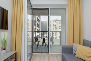 A private balcony with a seating area, offering a relaxing outdoor space with a view of the surrounding modern residential buildings.

