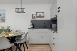 Another angle of the open kitchen and dining area, featuring white and black cabinetry, a minimalist pendant light, and a functional design.

