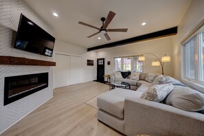 Living room where main closet has  extinguisher, highchair, extra dining chair.